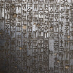 Close-up of the Code of Hammurabi, showing vertical columns of ancient cuneiform script carved into dark basalt. The wedge-shaped characters are deeply incised and weathered, with small chips and imperfections scattered across the surface. The texture of the stone highlights the precision and density of the writing, symbolizing the earliest codification of law and balance in Mesopotamian society.